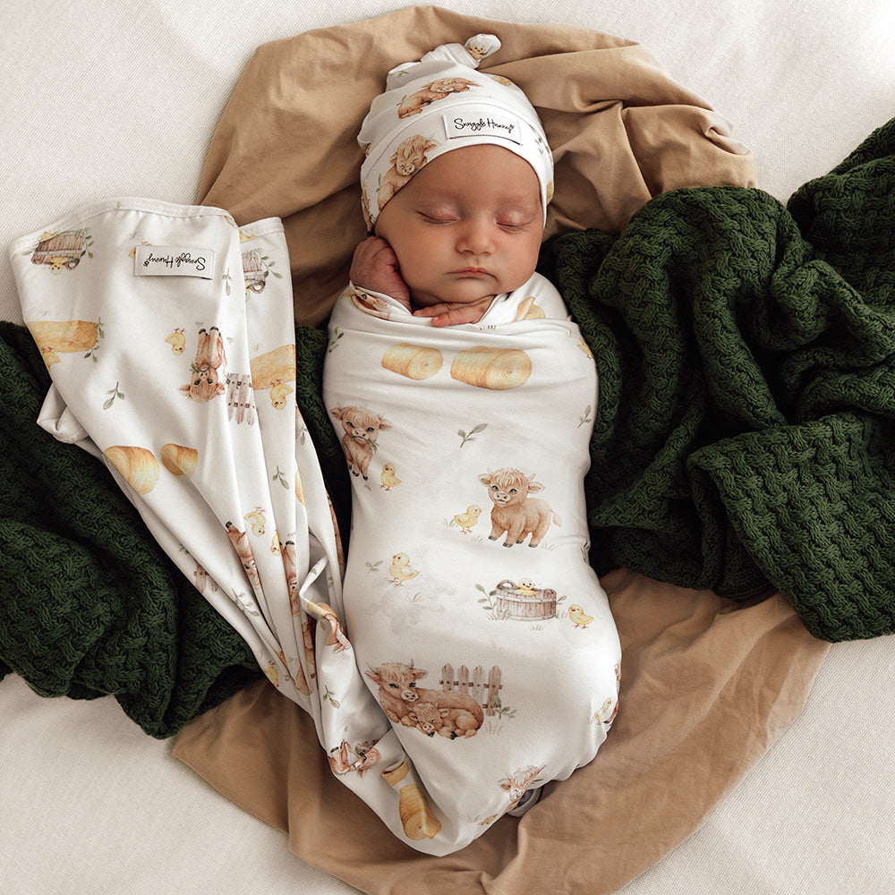 Newborn wrapped in Snuggle Hunny Highland Cows organic jersey wrap and beanie set