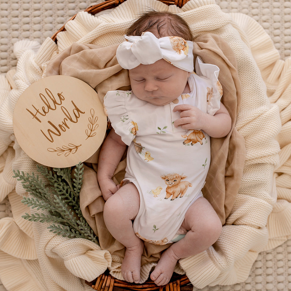 Baby wearing Snuggle Hunny Highland Cows short sleeve organic bodysuit with frill