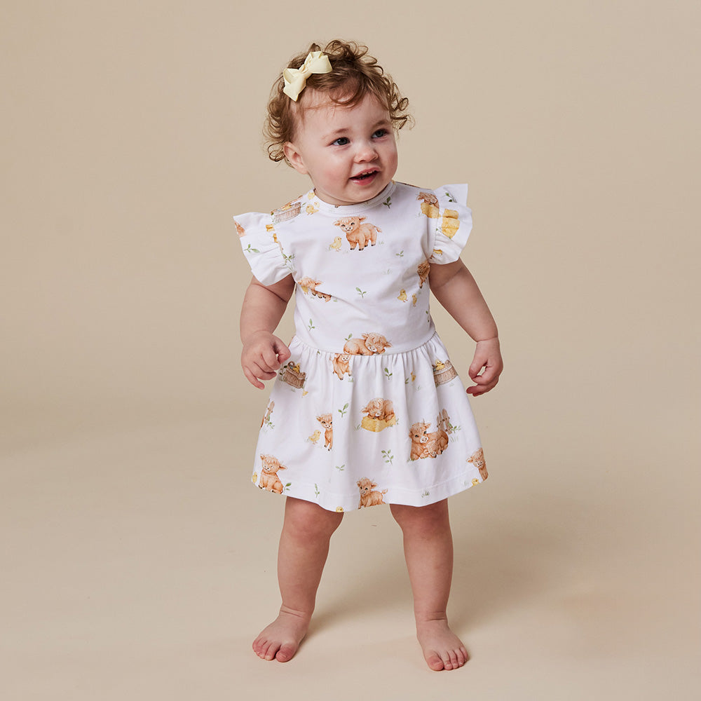 Baby wearing Snuggle Hunny Highland Cows short sleeve organic dress